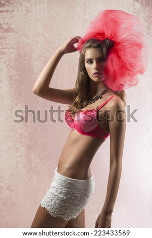 sensual young woman with red bra and sexy shorts in fashion pose with big carnival accessory on the head