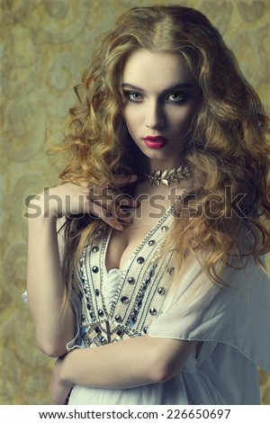 lovely sensual woman wearing antique clothes and jewellery and posing with long curly hair. fashion vintage portrait