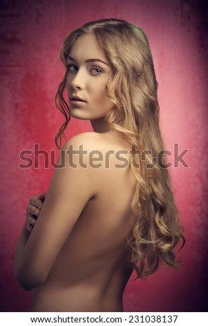 sensual naked girl posing turned on her back with amazing very long silky blonde wavy hair, lookin in camera
