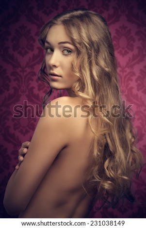 very pretty blonde woman with natural hair-style posing with beautiful long wavy silky hair and showing her naked back