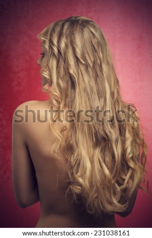 young nude woman posing turned on her back with cute long blonde wavy silky hair
