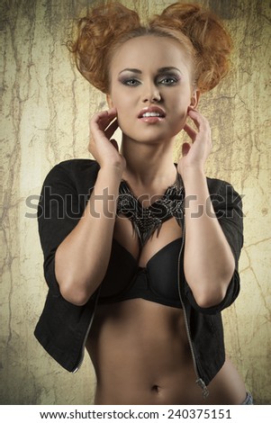 fashion shoot of cute redhead girl with bizarre pigtail hair-style, trendy necklace, black bra and jacket. Stylish make-up, cute style