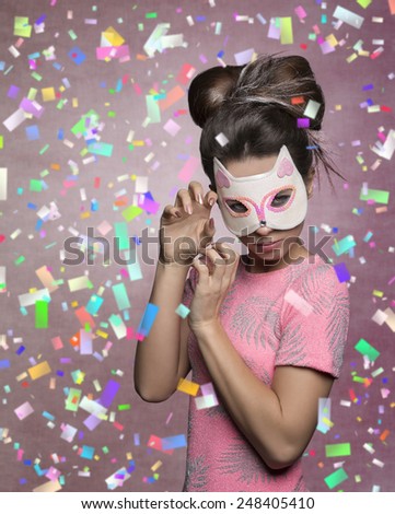 charming brunette girl masquerade with cat mask, in aggressive pose with creative hairdo and stylish pink t-shirt