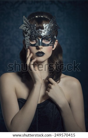 Beautiful, mysterious, sensual, woman with brown old fashion hairstyle, silver mask and dark makeup.