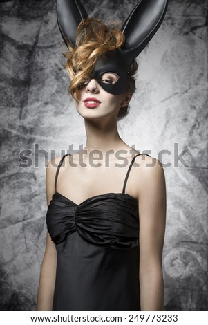 Sexy, lovely, charming woman in black bunny carnival mask and black dress. She has got red lips.