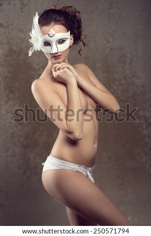 Beautiful, sexy, nude woman in white lingerie and white carnival mask with nice hairstyle and dark make up.