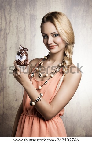 easter portrait of sexy blonde female with spring dress and jewellery showing funny small stuffed bunny toy