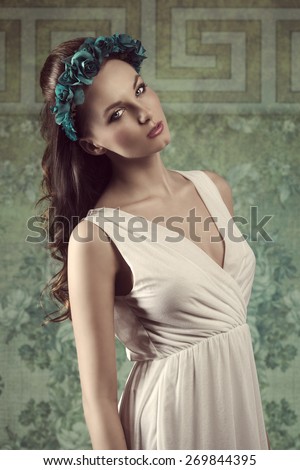 spring fashion portrait of romantic brunette woman with long hair, coloured flowers on the head and sexy white dress