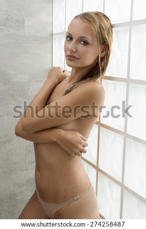 Blonde, natural, fresh, wet woman under the shower. She has got wet hair and all body. She is looking at camera.
