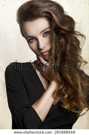 close-up portrait of very pretty young woman with nice make-up and long volume wavy hair. Wearing black  dress