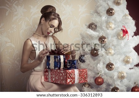 elegant beautiful woman with hair-style sitting near decorated tree with some Christmas presents. Xmas concept.