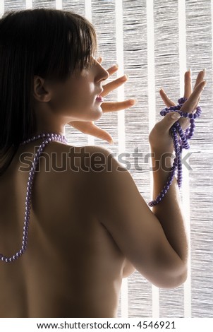 young and cute brunette with naked shoulder playing with a pearl string