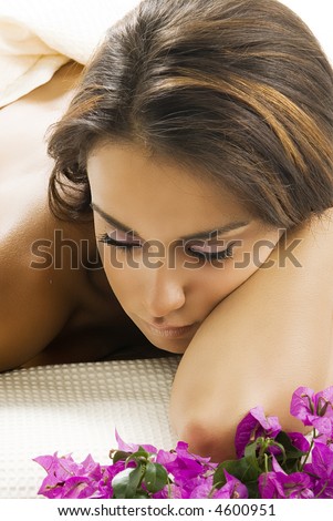a nice portrait of young and cute brunette laying down on a wood carpet with flowers near her