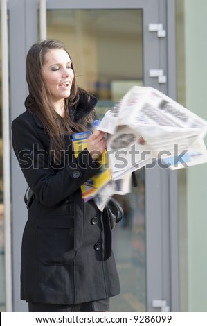 nice girl with black coat and news paper flying away