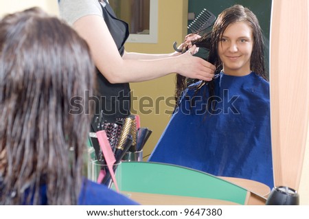 nice girl in a beauty salon while an hair stylist brush and dry her hair