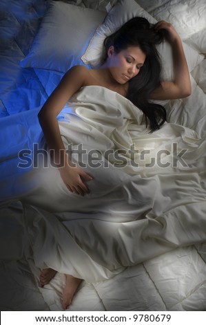 young and beautiful brunette sleeping between white sheet in the night