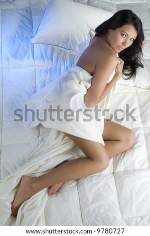 sexy brunette between the sheet looking in camera sensual