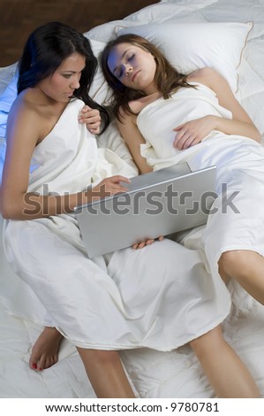 girls laying down on bed working together with a lap top