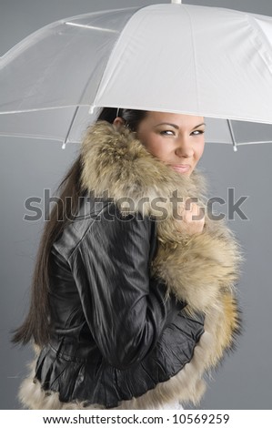 nice and young girl with umbrella and fur coat looking cold
