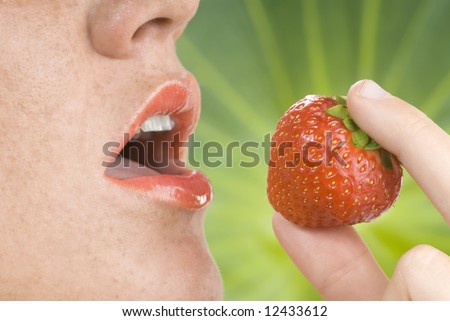 open mouth with red lipstick and a strawberry near focus on strawberry