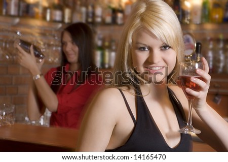 blond girl near the bar drinking a cocktail