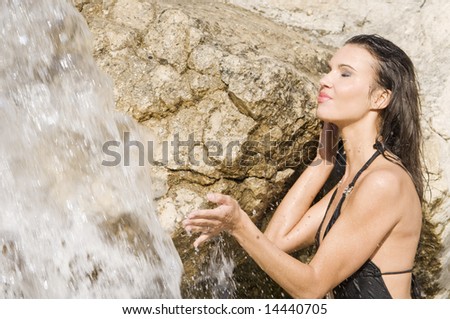 sensual portrait of a girl with hair and dress wet near a waterfall