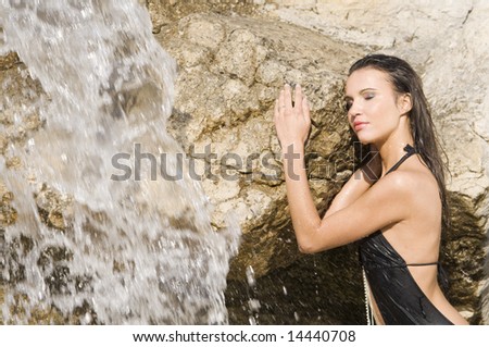 sensual portrait of a girl with hair and dress wet near a waterfall