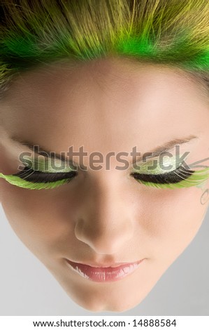 close up of a face of a girl with green eyelashes and yellow green hair