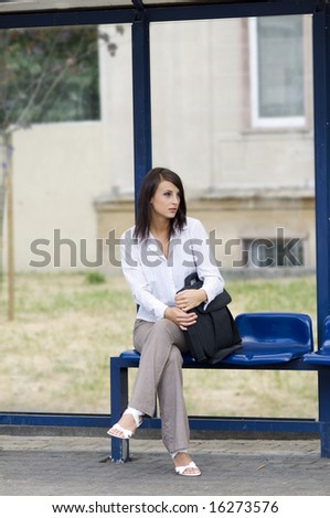 business woman sitting down at the bus stop waiting