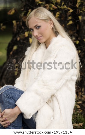 cute girl with blond long hair dressing a white fur in autumn park