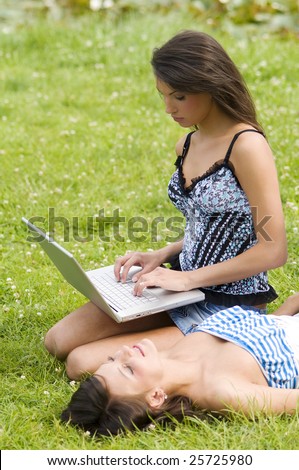 girls in a field one working on laptop other laying down to enjoy the sun
