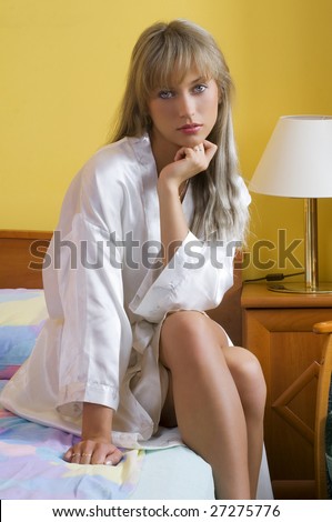cute blond woman in nightgown sitting on the border bed looking in you
