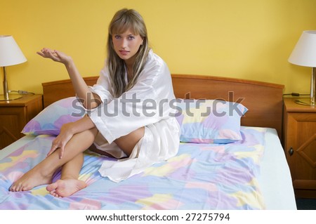 beautiful blond woman in nightgown sitting on bed and chatting with the camera