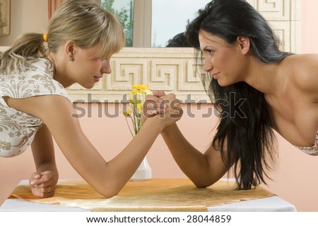 Two women arm wrestling at work on desk on white background