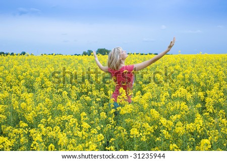 happy blond girl with open arms to the sky smiling in a yellow field