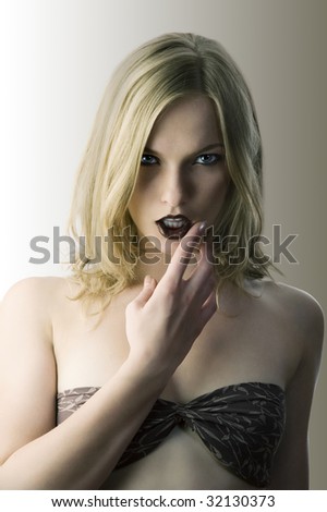 fashion portrait of a cute woman touching her mouth with finger and looking sexy