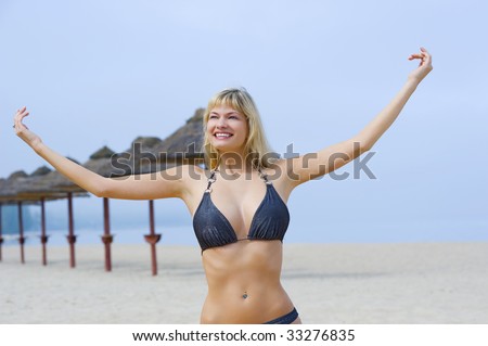 cute blond woman in bikini smiling with open arm