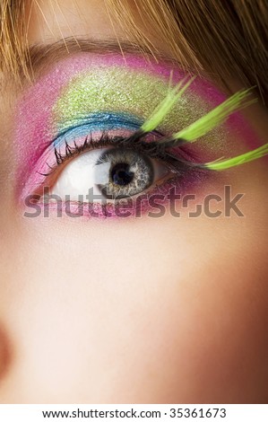 eye woman close up with colored make up and green eyelashes