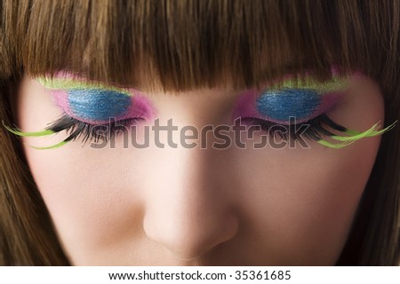 eyes close up of beautiful young woman with green eyelashes and vibrant color