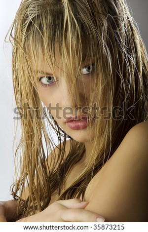 sensual and beautiful blond girl with long wet hair on her face looking the camera