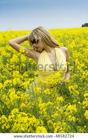 cute young blond woman outdoor in a yellow field wearing sun glasses and a yellow shirt