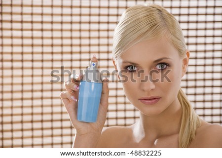 cute woman showing a bottle spray near her face in an advertising shot