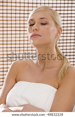 beauty advertising shot of a blond girl in act to be in a wellness farm with towel and cosmetic product