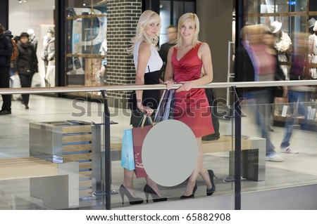two young beautiful and elegant woman inside a commercial center go for shopping with bags