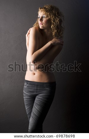 sexy shot of young woman with naked shoulder and curly hair on black background