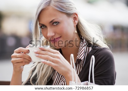 A young woman sitting alone in a cafe outdoor and drinking a cup of tea