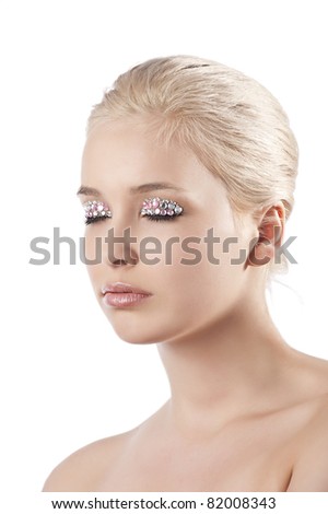 very cute blond young woman with hair style with some shining gem stone on her eyes as a creative make up