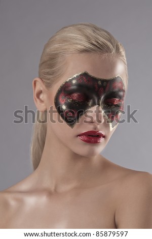 face shot of a pretty blonde with red lipstick and a carnival mask painted on her face