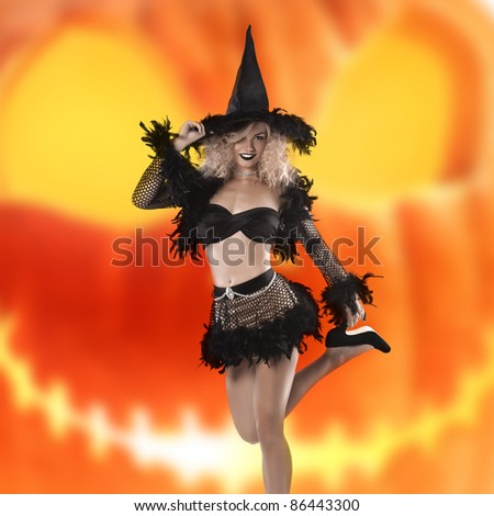 glamour shot of a cute and curled blonde posing in a black witch costume and high heels