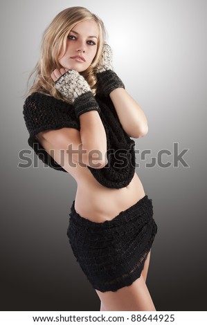 sexy blond girl in topless wearing a black wool scarf around her neck and covering her body like a skirt, sheâ?? s positioned of Â¾, looks at the lens and her hands are near the face.